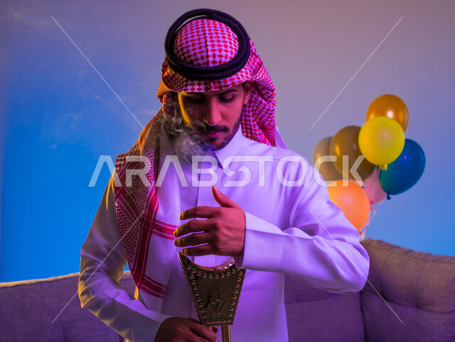 A Saudi Arab man carries the incense burner, the incense holder, the use of oud wood in social and religious occasions, perfume and perfume, the feast in Saudi society, the joy and joy of the feast, the celebration of the happy feast