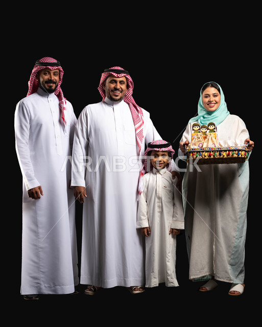 بورتريه لعائلة عربية خليجية سعودية ترتدي الزي التقليدي السعودي ،  سلة مليئه بقرقيعان وتوزيعات العيد ،إيماءات وجه تدل على الفرح والسعادة ،أجواء العيد في السعودية ، الاحتفال في أيام العيد السعيد ، النظر إلى الكاميرا ، خلفية سوداء