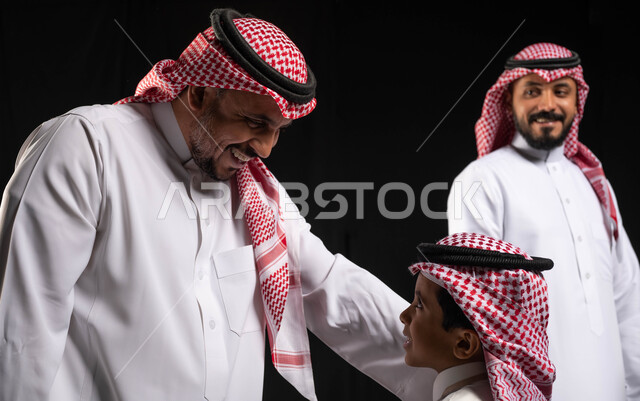 الاحتفال بقدوم العيد ، بورتريه لعائلة عربية خليجية سعودية ترتدي الثوب التقليدي السعودي ، إيماءات وجه تدل على الفرح والسعادة  ،أجواء العيد في السعودية ، خلفية سوداء