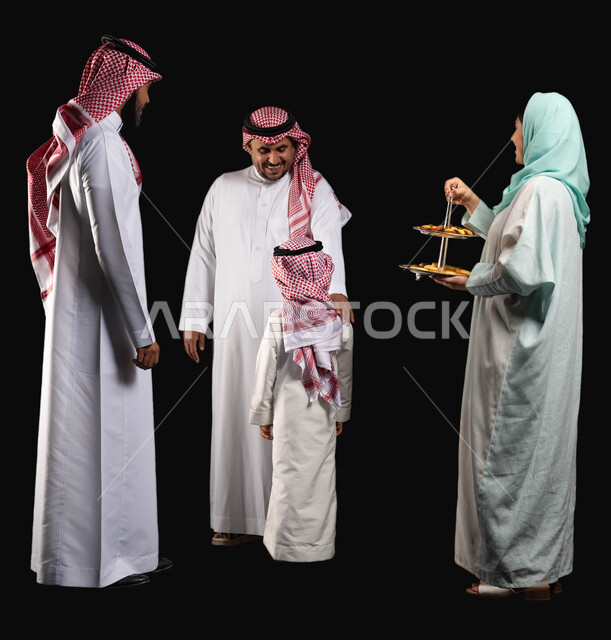 تقديم الضيافة وحلوى العيد ، عائلة عربية خليجية سعودية ترتدي الزي التقليدي السعودي ، إيماءات وجه تدل على الفرح والسعادة ، الاحتفال بقدوم العيد ،  امراه عربيه سعوديه خليجيه تقوم بتقديم حلوى العيد للضيوف ، صورة الجسم بالطول الكامل ، خلفية سوداء