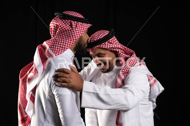 بورتريه مقرب لرجل عربي سعودي خليجي يرتدي الزي السعودي التقليدي يقوم بتقبيل رأس جده , أجواء عائليه سعيده, عيد مبارك, المناسبات والاعياد الاسلاميه, التجمعات الأسريه في العيد السعيد ، خلفيه سوداء