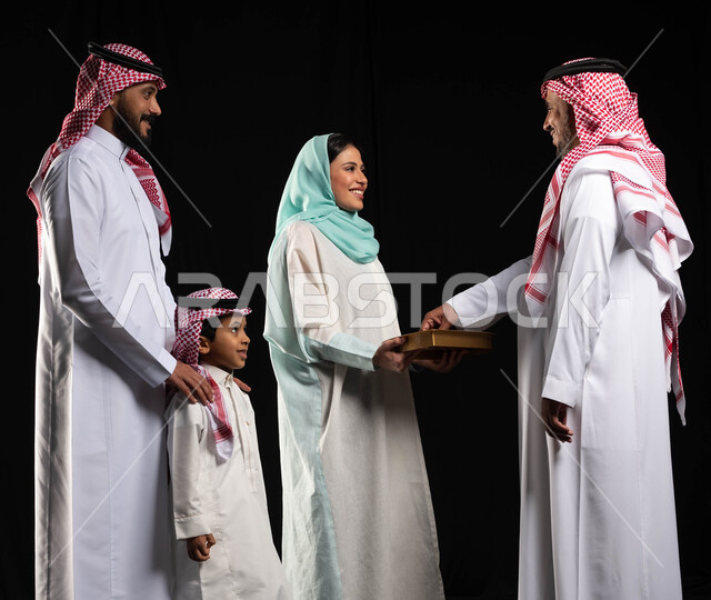 بورتريه لشابة عربيه سعوديه خليجيه تقوم بتقديم حلوى العيد للضيوف ، عائلة عربية خليجية سعودية تحتفل بقدوم العيد , مناسبات واعياد اسلاميه, زيارات وتجمعات عائليه, اكرام الضيف وحسن الاستقبال, خلفيه سوداء