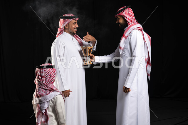 بورتريه لطفل صغير يرتدي الزي السعودي التقليدي ، الاحتفال بقدوم العيد ، استخدام خشب العود ،أجواء العيد في السعودية ، رجلان عربيان خليجيان سعوديان يرتديان الزي السعودي التقليدي  ، حامل البخور( المبخرة ) ، التطيب والتعطر ، خلفية سوداء