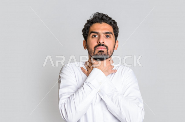 بورتريه لرجل عربي سعودي خليجي يرتدي الثوب السعودي , يقوم بإيماءات وجه و يدين تدل على الاختناق والشعور بضيق التنفس ، الأمراض النفسية , الإكتئاب , الرغبة بالإنتحار , الإحساس بالخوف وعدم الأمان ، خلفية بيضاء .