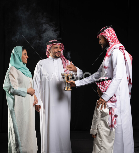 استخدام خشب العود ، التطيب والتعطر ، أجواء العيد في السعودية ، بورتريه لأمرأه عربية خليجية سعودية محجبة تحمل حامل البخور( المبخرة ) ، رجل عربي خليجي سعودي يرتدي الزي التقليدي السعودي  ، خلفية سوداء