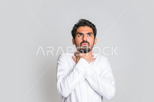 بورتريه لرجل عربي سعودي خليجي يرتدي الثوب السعودي , يقوم بإيماءات وجه و يدين تدل على الاختناق والشعور بضيق التنفس ، الأمراض النفسية , الإكتئاب , الرغبة بالإنتحار , الإحساس بالخوف وعدم الأمان ، خلفية بيضاء .