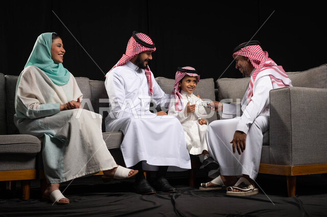 تبادل أطراف الحديث، بورتريه لعائلة عربية خليجية سعودية  تحتفل بقدوم العيد السعيد ، الاحتفال بقدوم العيد ، تقديم العيديات للأطفال, ايماءات تدل على الفرح والسرور بالعيد السعيد, مناسبات واعياد اسلاميه, خلفيه سوداء