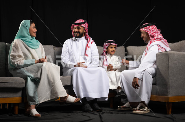 بورتريه لعائله عربيه سعوديه خليجيه سعيده ، تقديم العيديات للأطفال ، الزيارات والتجمعات الاسريه , إرتداء اللباس السعودي التقليدي في الأعياد والمناسبات , ايماءات تدل على الفرح والسرور بالعيد السعيد, مناسبات واعياد اسلاميه, خلفيه سوداء