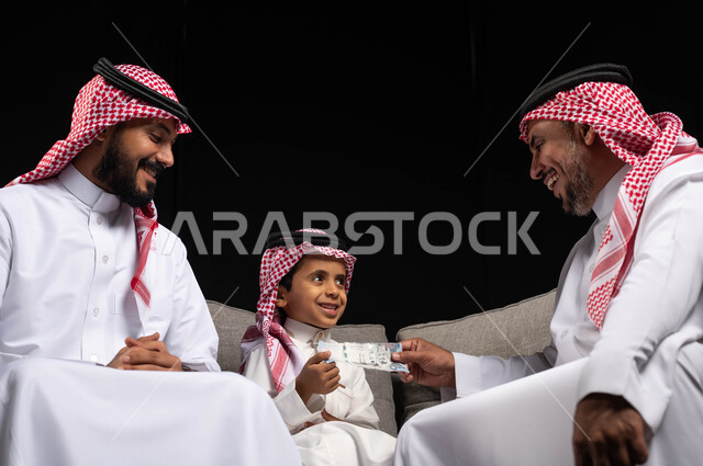 تقديم العيديات للأطفال ، الزيارات والتجمعات الاسريه ، بورتريه لعائله عربيه سعوديه خليجيه سعيده, إرتداء اللباس السعودي التقليدي في الأعياد والمناسبات , ايماءات تدل على الفرح والسرور بالعيد السعيد, مناسبات واعياد اسلاميه, خلفيه سوداء