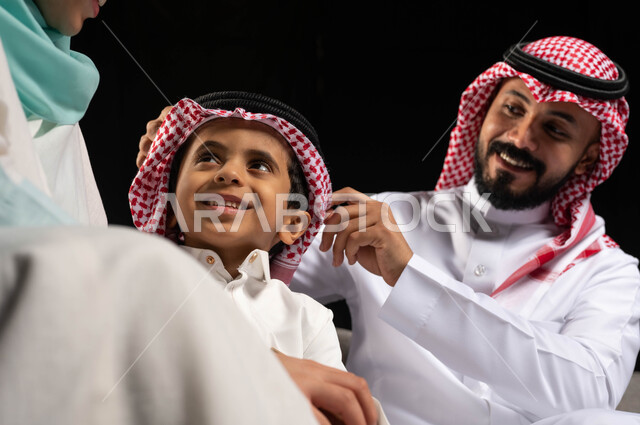 بورتريه لعائلة خليجية سعودية مبتسمة  تحتفل بالعيد  ، ارتداء اللباس السعودي التقليدي ،  ايماءات تدل على السعاده والسرور بالعيد السعيد, الزيارات العائليه والتجمعات الاسريه, الأعياد الاسلاميه في المملكه العربيه السعوديه ، خلفية سوداء
