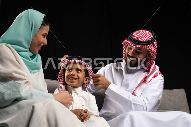 بورتريه لعائلة خليجية سعودية مبتسمة تحتفل بالعيد ، أجواء العيد في السعودية ، ارتداء اللباس السعودي التقليدي ، الأعياد الاسلاميه في المملكه العربيه السعوديه ، خلفية سوداء