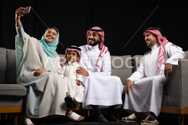 التقاط صور سيلفي لعائلة خليجية سعودية مبتسمة تحتفل بالعيد ، أجواء العيد في السعودية ، ارتداء اللباس السعودي التقليدي ، عيد الفطر المبارك ، عيد الأضحى ، زيارات العيد ، خلفية سوداء