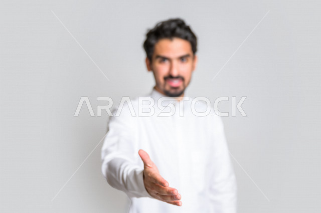 بورتريه لرجل عربي سعودي خليجي يرتدي الثوب السعودي , إيماءات يد تدل على المصافحه , التحيه والسلام, الموافقه والقبول, تعارف و صداقه, الشعور بالإيجابيه, الرضى والسرور , خلفية بيضاء .