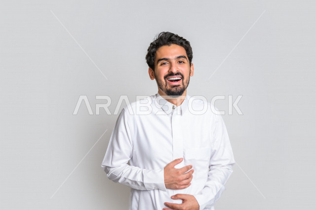 بورتريه لرجل عربي سعودي خليجي باللباس التقليدي , يقوم بإيماءات وجه تدل على الضحك بهستيريا ، إشارات يدين تدل على الفرحة والسعادة ، خلفية بيضاء .