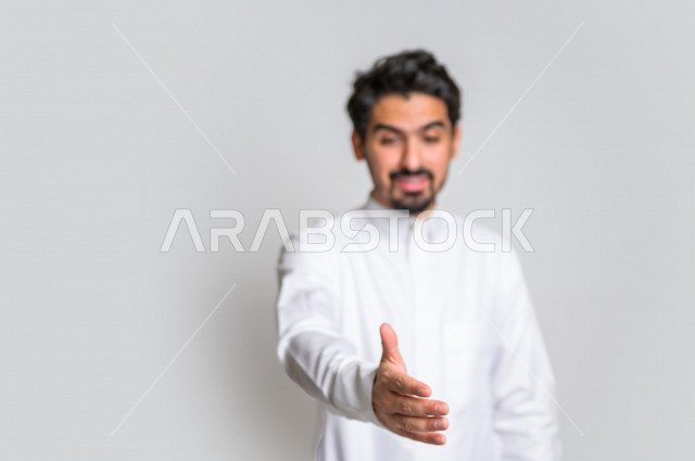 بورتريه لرجل عربي سعودي خليجي يرتدي الثوب السعودي , إيماءات يد تدل على المصافحه , التحيه والسلام, الموافقه والقبول, تعارف و صداقه, الشعور بالإيجابيه, الرضى والسرور , خلفية بيضاء .