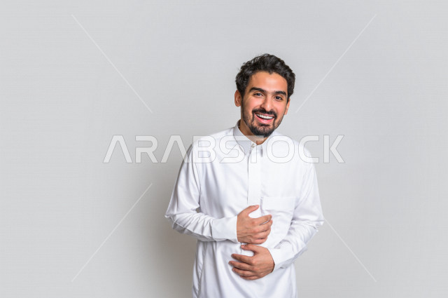 بورتريه لرجل عربي سعودي خليجي باللباس التقليدي , يقوم بإيماءات وجه تدل على الضحك بهستيريا ، إشارات يدين تدل على الفرحة والسعادة ، خلفية بيضاء .