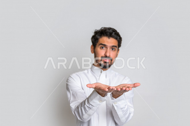 بورتريه لرجل عربي سعودي خليجي باللباس التقليدي , إيماءات وجه مختلفة ، إشارات يدين تدل على حمل شيء ما ، خلفية بيضاء .