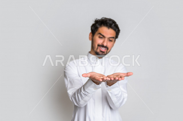 Portrait of a Saudi Arabian Gulf man in traditional dress, different facial gestures, hand gestures indicating carrying something, white background.