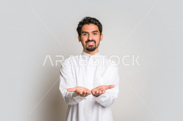 بورتريه لرجل عربي سعودي خليجي باللباس التقليدي , إيماءات وجه مختلفة ، إشارات يدين تدل على حمل شيء ما ، خلفية بيضاء .