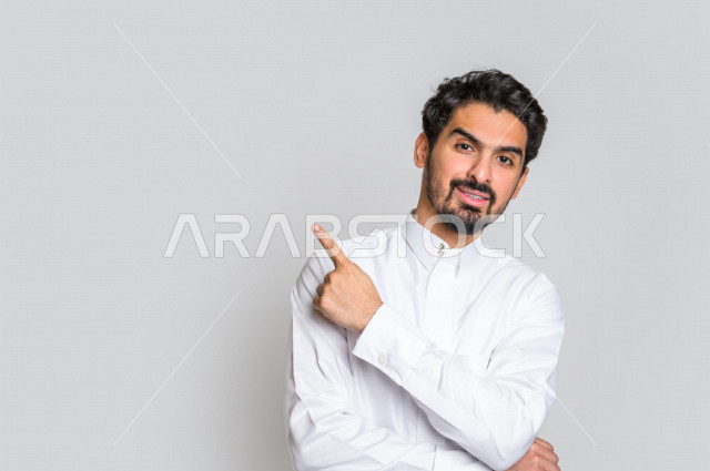 بورتريه لرجل عربي سعودي خليجي باللباس التقليدي , يؤشر بإصبعه لأعلى , إيماءات وجه مختلفة ، إشارات يدين مختلفة ، خلفية بيضاء .