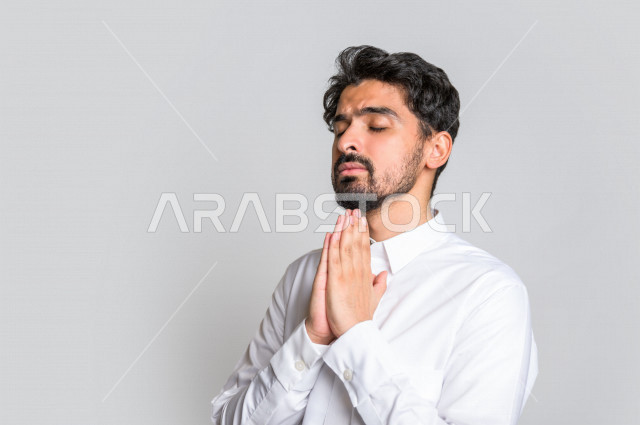 Portrait of a Saudi Arabian Gulf man, wearing traditional Saudi dress, raising his hands up and supplicating to God with different facial and hands gestures denoting supplication and supplication, concept of supplication and need, worship and getting clos
