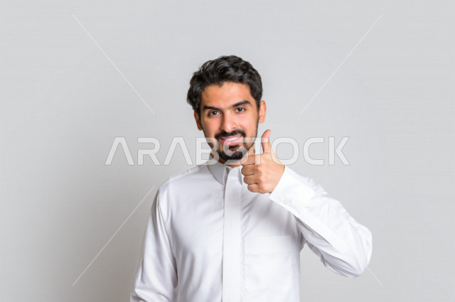 Portrait of a Saudi Arabian Gulf man in traditional dress, making facial gestures indicating happiness, hand gestures indicating happiness, white background.