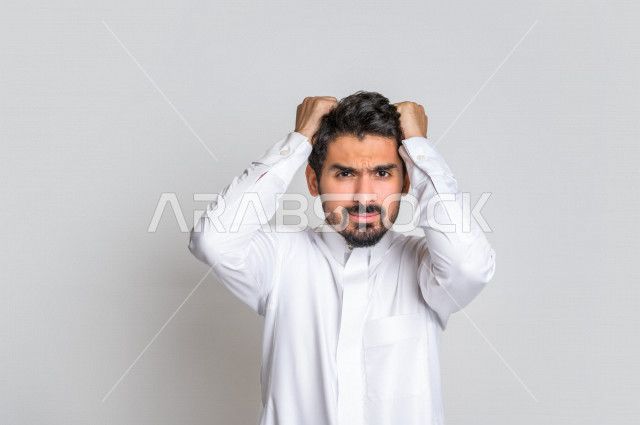 بورتريه رجل عربي سعودي خليجي باللباس التقليدي , يقوم بإيماءات وجه تدل على العصبية والندم , إشارات يد تدل على الخسارة والفشل , خلفية بيضاء .