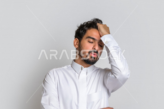 بورتريه رجل عربي سعودي خليجي باللباس التقليدي , يقوم بإيماءات وجه تدل على العصبية والندم , إشارات يد تدل على الخسارة والفشل , خلفية بيضاء .