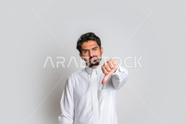 بورتريه رجل عربي سعودي خليجي باللباس التقليدي , يقوم بإيماءات وجه تدل على الندم , إشارات يد تدل على الخسارة والفشل , خلفية بيضاء .