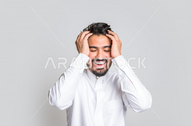 بورتريه لرجل عربي سعودي خليجي باللباس التقليدي , يقوم بإيماءات وجه تدل على الضحك بهستيريا ، إشارات يدين تدل على الفرحة والسعادة ، خلفية بيضاء .