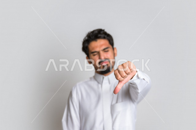 بورتريه رجل عربي سعودي خليجي باللباس التقليدي , يقوم بإيماءات وجه تدل على الندم , إشارات يد تدل على الخسارة والفشل , خلفية بيضاء .