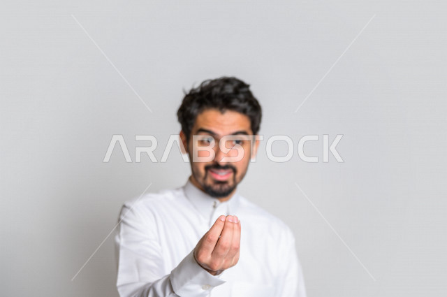 بورتريه لرجل سعودي خليجي باللباس التقليدي , يقوم بإيماءات وجه مختلفة ، إشارة يد تدل على الإنتظار والصبر ، خلفية بيضاء