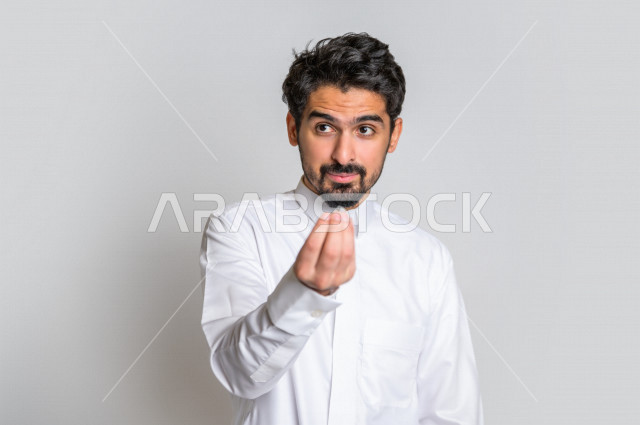بورتريه لرجل سعودي خليجي باللباس التقليدي , يقوم بإيماءات وجه مختلفة ، إشارة يد تدل على الإنتظار والصبر ، خلفية بيضاء