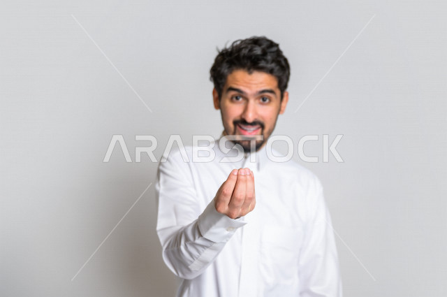 بورتريه لرجل سعودي خليجي باللباس التقليدي , يقوم بإيماءات وجه مختلفة ، إشارة يد تدل على الإنتظار والصبر ، خلفية بيضاء