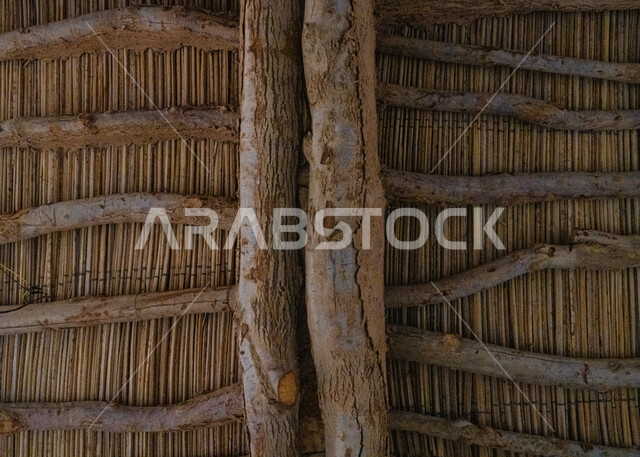صورة مقربة لحائط مصنوع من جذع الاشجار، اسقف وجدران المنازل القديمة، سقف خشبي من جذوع الاشجار مع خوص النخيل