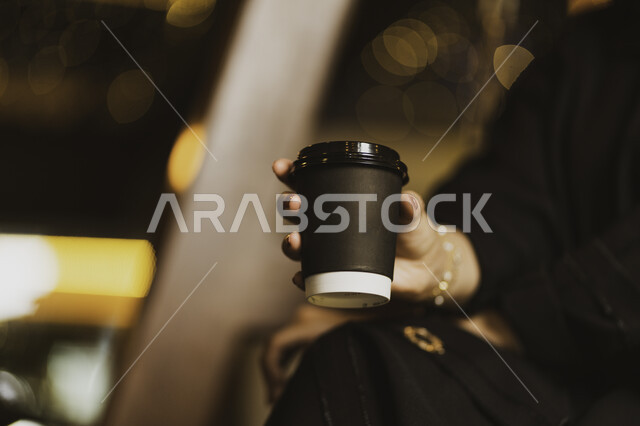 Entertainment and entertainment in the cafes of the Kingdom of Saudi Arabia, ordering coffee from the Saudi coffee shop for a Saudi Arab woman who drinks coffee, enjoying drinking coffee in a quiet atmosphere and spending quality time outside the house