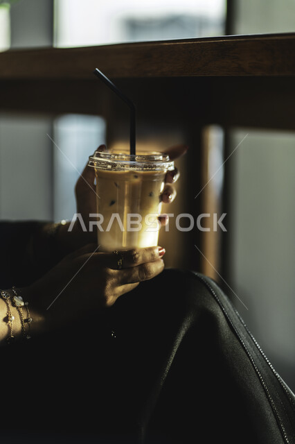 الإستمتاع بشرب القهوه في أجواء هادئه وقضاء وقت ممتع خارج المنزل ، طلب القهوه من متجر القهوه السعودي لإمرأه عربيه سعوديه تشرب القهوة ، تسليه وترفيه في مقاهي المملكه العربيه السعوديه