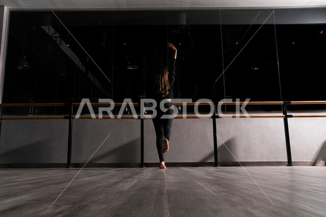 Maintaining health and physical fitness, practicing gymnastics in the women's sports club, a picture from behind of a Saudi Arabian Gulf woman wearing a sports uniform, Pilates and stretching movements