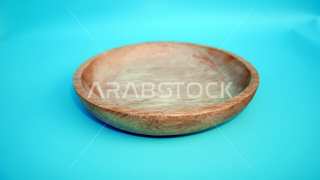 صورة مقربة لطبق خشبي فارغ، حرف وصناعات يدوية، طبق مصنوع من الخشب، خلفية زرقاء