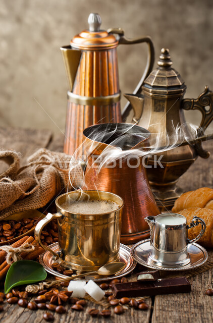 A set of Arab copper utensils with a coffee pot and cups, coffee made in the oriental way, a group of scattered coffee beans, stimulant and caffeine drinks