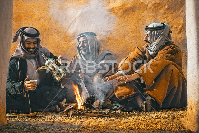 صورة مقربة لمجموعة من الرجال العرب السعوديون، الجلوس في الأحياء الشعبية مع شعلة الحطب، يوم التأسيس السعودي، تأسيس المملكة 1727م ، أزياء شعبية سعودية، بيوت طينية تراثية قديمة، زي تراثي سعودي للمناسبات الوطنية