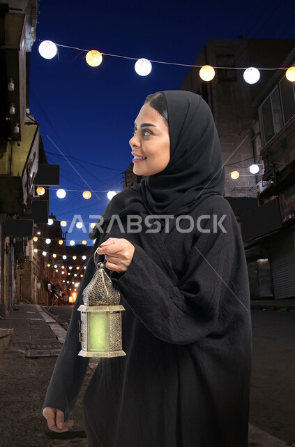 امرأة سعودية عربية خليجية تمسك فانوس رمضان، شهر رمضان المبارك، استقبال شهر رمضان المبارك، إضاءة وزينة شهر رمضان، أجواء رمضانية ليلية، المناسبات الدينية والأعياد الإسلامية