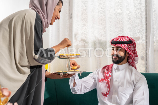 الزيارات و التجمعات الاسريه في الأعياد والمناسبات و التهنئه بقدوم العيد, سيدة عربية سعودية خليجية تقوم بتقديم حلوى العيد السعيد , بهجة وفرحة العيد,  حسن استقبال واكرام الضيوف, العيد بين الاهل, ايماءات تدل على الفرح والسعاده