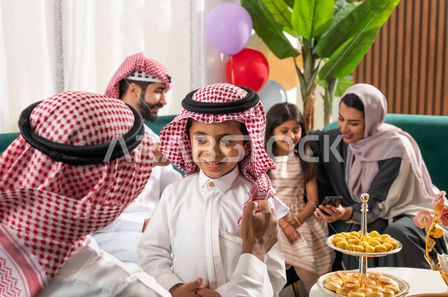 Online video calls via mobile phone, conversations, chats and social communication using the mobile device, a family gathering of a Saudi Gulf Arab family sitting in the living room, gestures indicating happiness, spending quality time, a pleasant family 