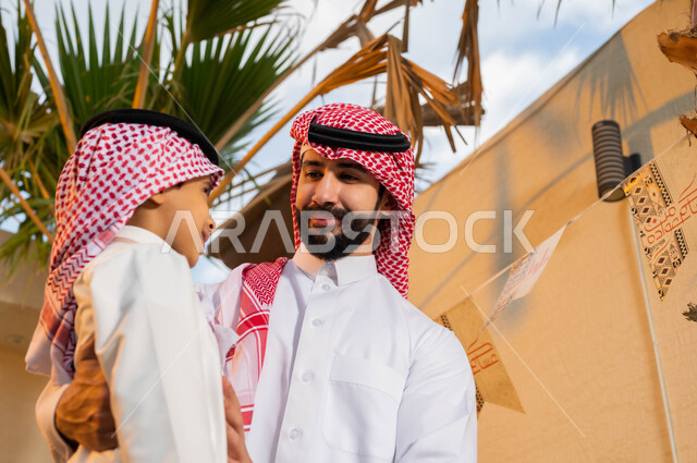 الاحتفال بقدوم العيد, ارتداء الزي السعودي التقليدي, صورة مقربة لرجل عربي خليجي سعودي مع ابنه يحتفلون في العيد, ديكورات وزينة العيد السعيد, أعياد ومناسبات اسلامية .