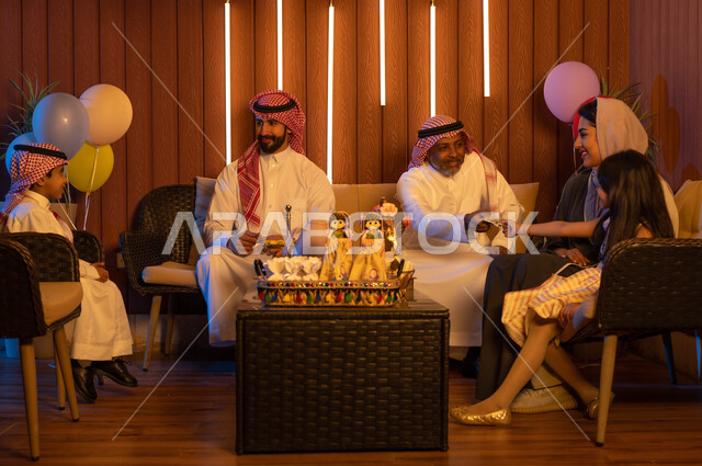 تجمع عائلي لأسرة عربية خليجية سعودية في غرفة الجلوس تحتفل بالعيد, تقديم العيديات وقرقيعان العيد السعيد, ايماءات تدل على الفرح والسرور, التهنئة بقدوم العيد المبارك, أعياد ومناسبات اسلامية.