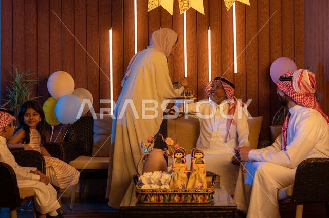 حسن استقبال واكرام الضيوف,  ايماءات تدل على الفرح والسعاده, عائلة عربية خليجية سعودية تحتفل بالعيد, تقديم حلوى وكعك العيد , التهنئه بقدوم العيد في الأعياد والمناسبات الاسلامية السعيدة ,الزيارات و التجمعات الاسريه .