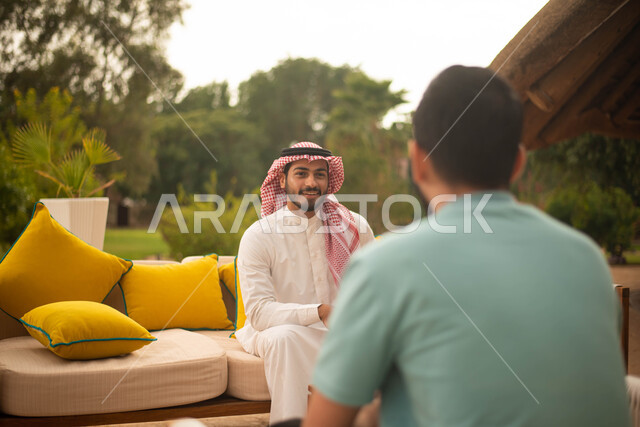 Gestures indicating joy and pleasure for two young Saudis, Arabs, Gulf Saudis, spending fun times in the open air, youth sessions and activities, discussions and dialogues, people and acquaintances, young people, green nature