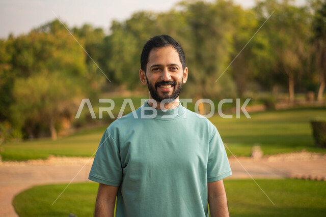 النظر إلى الكاميرا ، رجل عربي خليجي سعودي يقضي أوقات ممتعة في إحدى الحدائق في السعودية ، نزهه في الهواء الطلق، جولة في الطبيعة الخضراء