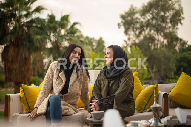 قضاء أوقات ممتعة في الطبيعة الخضراء والجلوس في الهواء الطلق ، صديقتان عربيتان خليجيتان سعوديتان تستمتعان بتبادل الحديث، صداقات وتعارف ونقاشات وحوارات